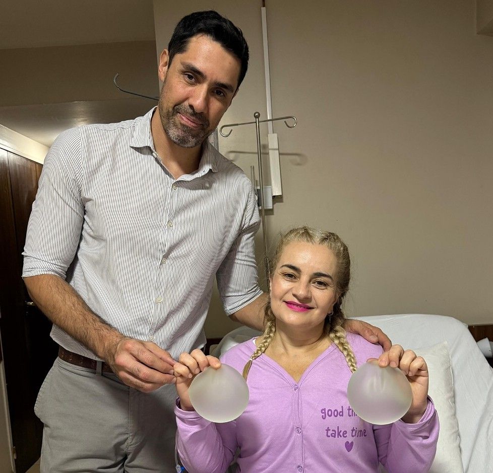 El doctor junto a una paciente que sostiene los implantes que se le retiraron